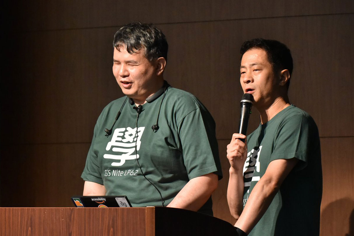 写真:目を閉じて微笑んでいる辻さんと、マイクを持ってお話中の植木さん。辻さんはピンマイクをつけて、イヤホンを肩から下げている