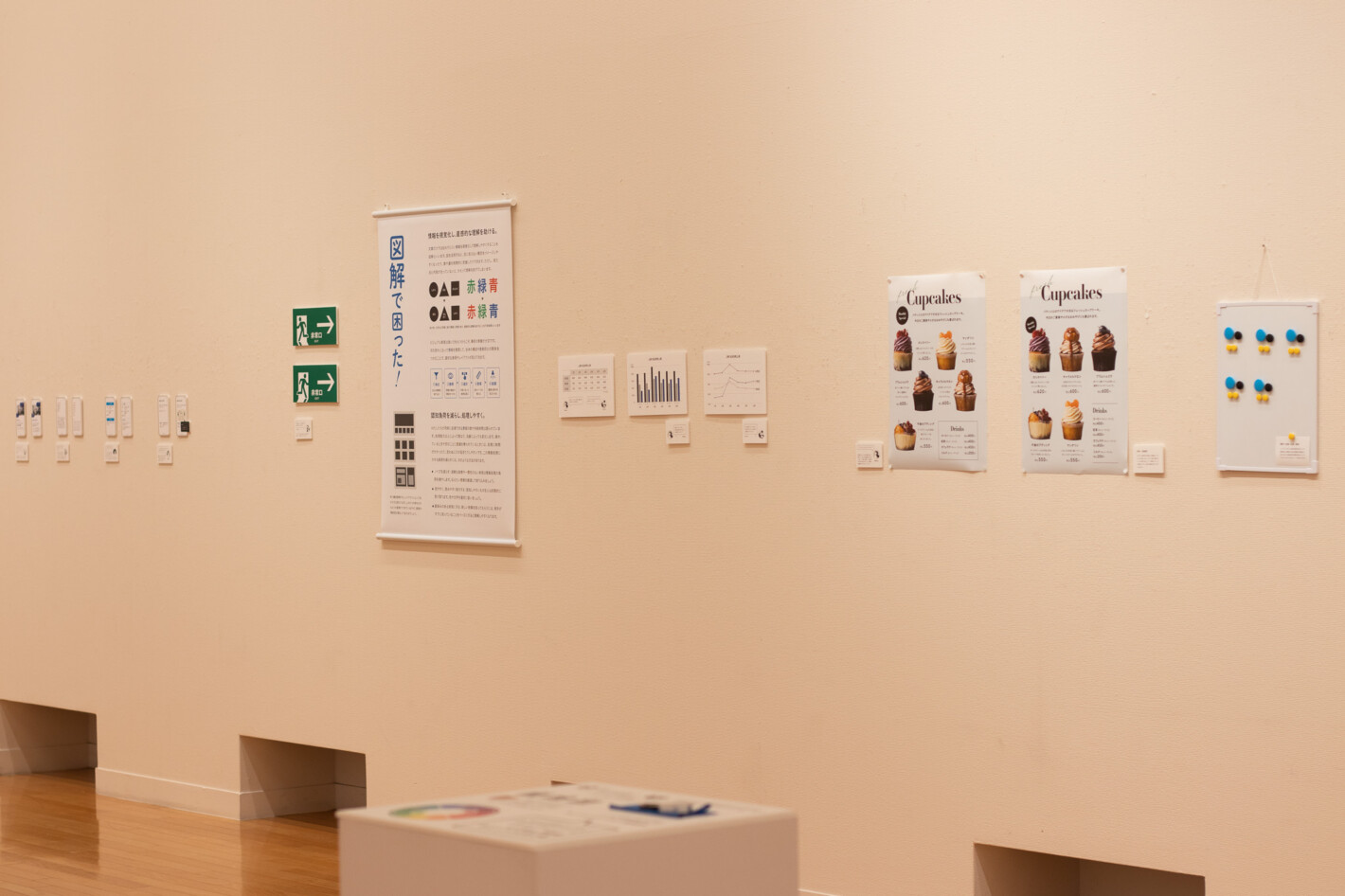 写真:「図解で困った!」というタペストリーや、非常口のサイン、グラフのパネルやポスターが壁に展示されています