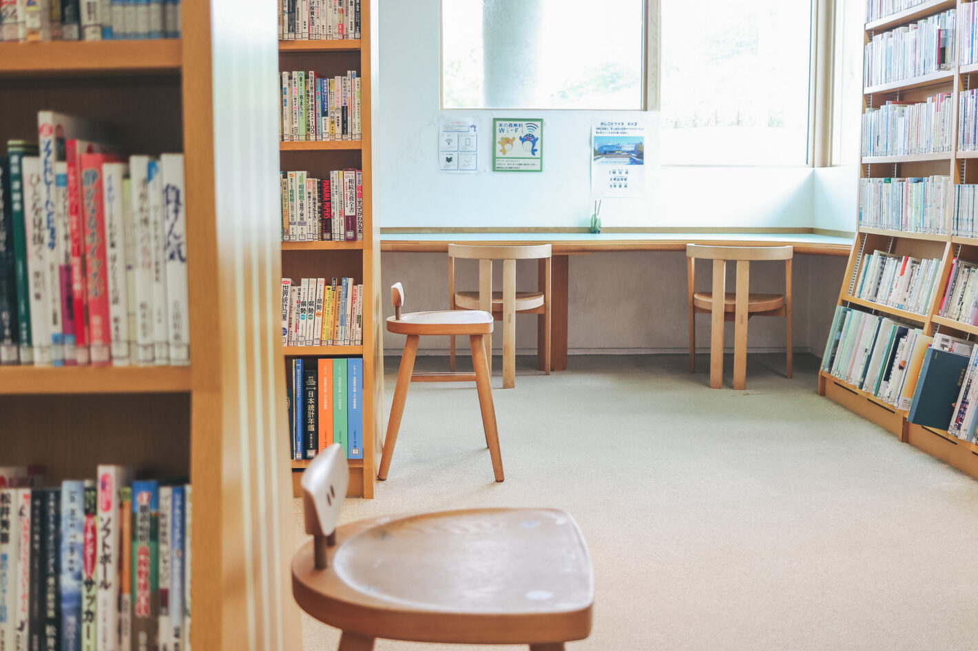 写真:図書館の風景。本棚の側、カウンター席に合わせて、それぞれ木製の椅子が置いてあります。